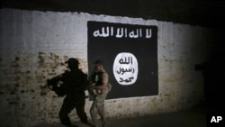 ILE - In this March 1, 2017 photo, an Iraqi soldier inspects a tunnel, adorned with an Islamic State flag.