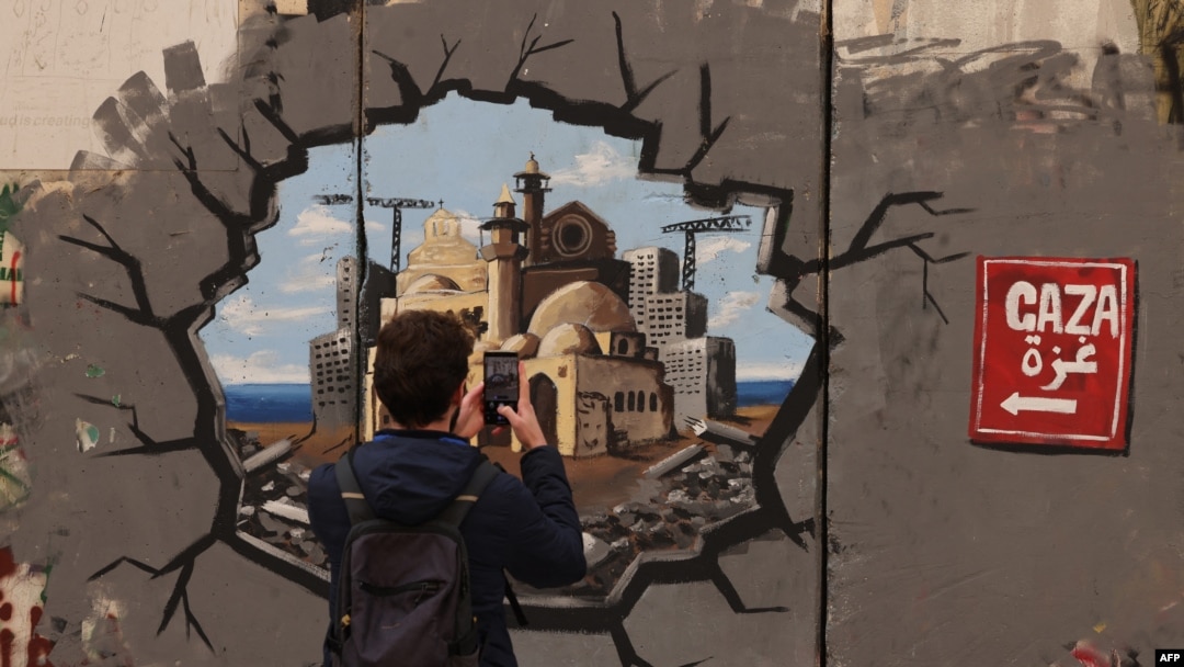 Un hombre toma una foto de un grafiti que representa la reconstrucción de Gaza en Belén, el 12 de febrero de 2025. AFP/Hazem Bader