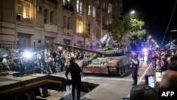 Para pejuang kelompok tentara bayaran swasta Grup Wagner menarik diri dari markas Distrik Militer Selatan, untuk kembali ke pangkalan mereka di kota Rostov-on-Don, Rusia dekat perbatasan Ukraina. (Reuters) 
