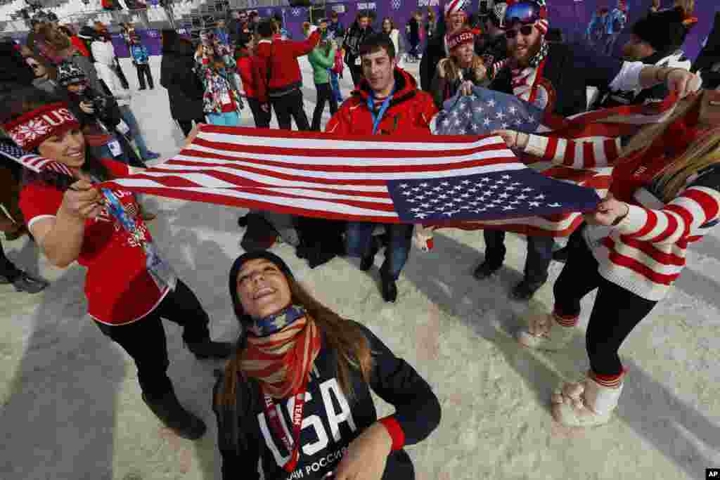 Fans limbo dance under a U.S. flag to celebrate Jamie Anderson's gold medal in the women's snowboard slopestyle final, in Krasnaya Polyana, Russia, Feb. 9, 2014.