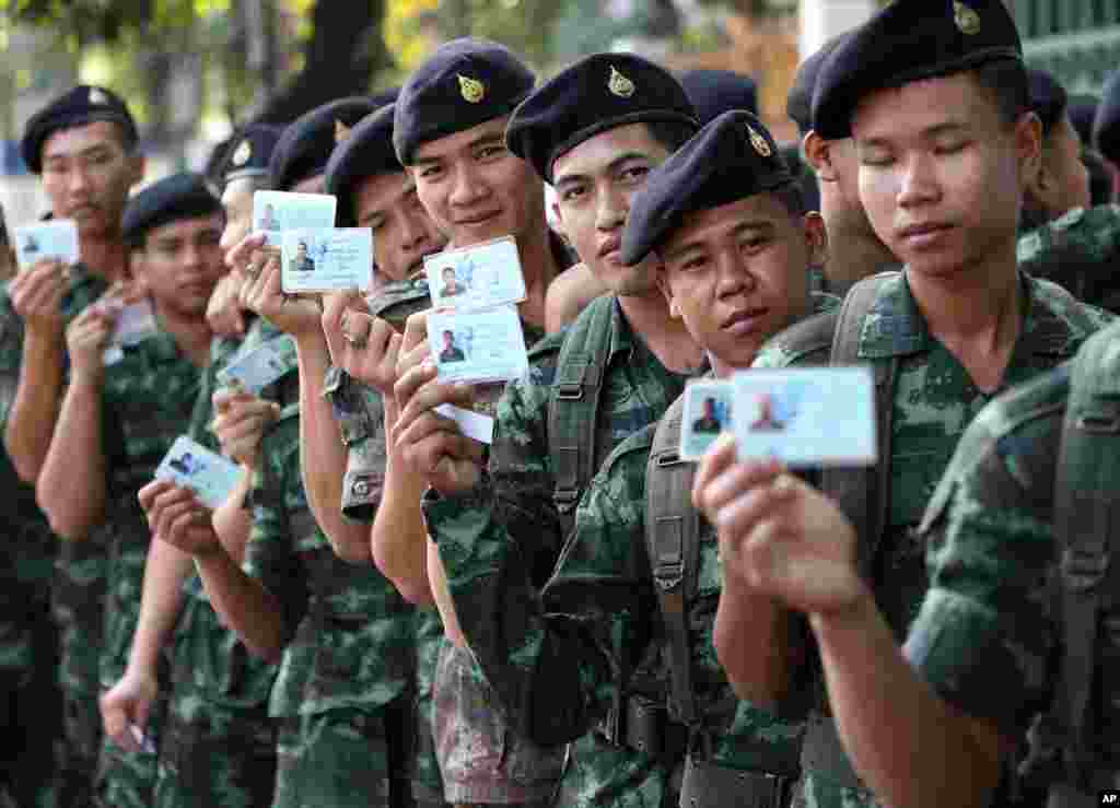 Thai soldiers pose with their identity cards as they wait in a line to vote at a polling station in Bangkok, Feb. 2, 2014.