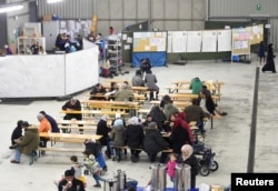 FILE - Migrants sit in a canteen in a refugee camp in Celle, Lower-Saxony, Germany, Oct. 15, 2015.