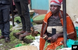 A woman shells peas at a street market in Abugarama, a mountain village near Bujumbura, Burundi, Dec. 14, 2015.