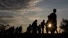 Migrants walk along rail tracks as they arrive at a collection point in the village of Roszke, Hungary, Sept. 8, 2015, after crossing the border from Serbia.