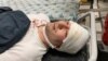 FILE - Blogger Miraziz Bazarov lies on a stretcher upon his arrival at a hospital after he was beaten by a group of unidentified men in Tashkent, Uzbekistan March 29, 2021.