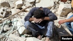 A man reacts on the rubble of damaged buildings after losing relatives to an airstrike in the besieged rebel-held al-Qaterji neighborhood of Aleppo, Syria, Oct. 11, 2016.