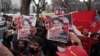 Warga Myanmar yang tinggal di Jepang dan pendukungnya memegang foto pemimpin Myanmar Aung San Suu Kyi saat melakukan protes di depan Kementerian Luar Negeri di Tokyo, Rabu, 3 Februari 2021. (Foto: AP)