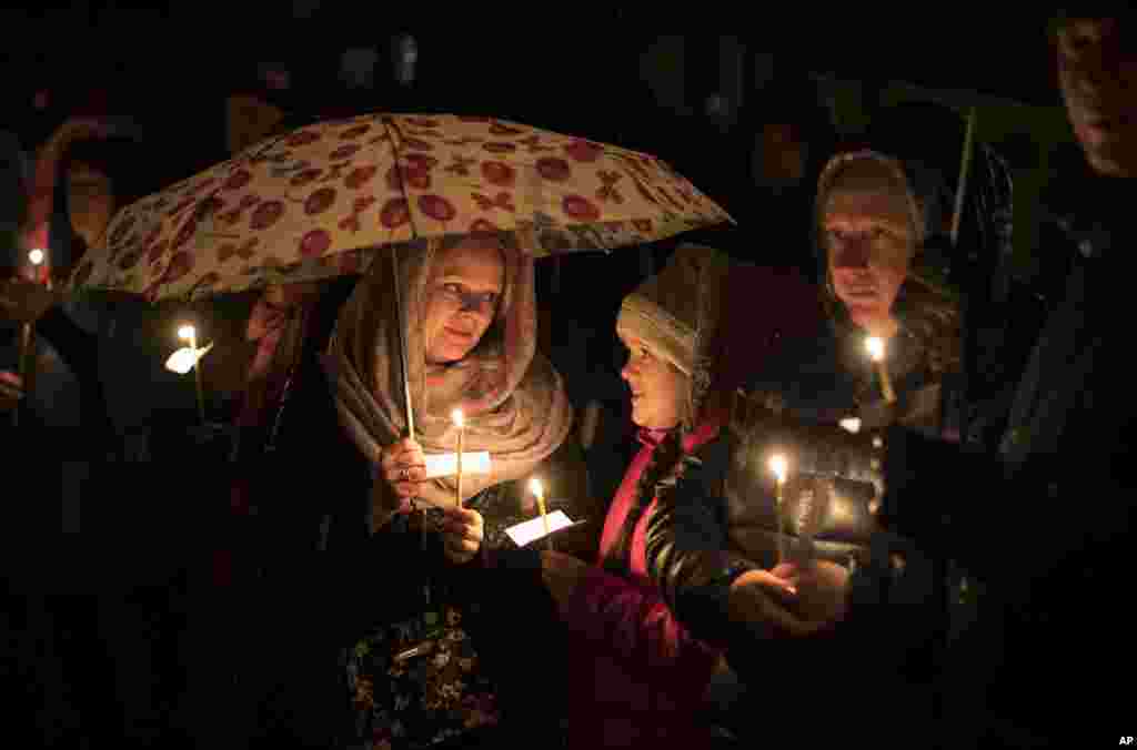 Lithuanian Orthodox believers hold candles and pray during an Easter vigil mass in the Prechistensky, the Cathedral Palace in Vilnius, Lithuania, April 15, 2017.