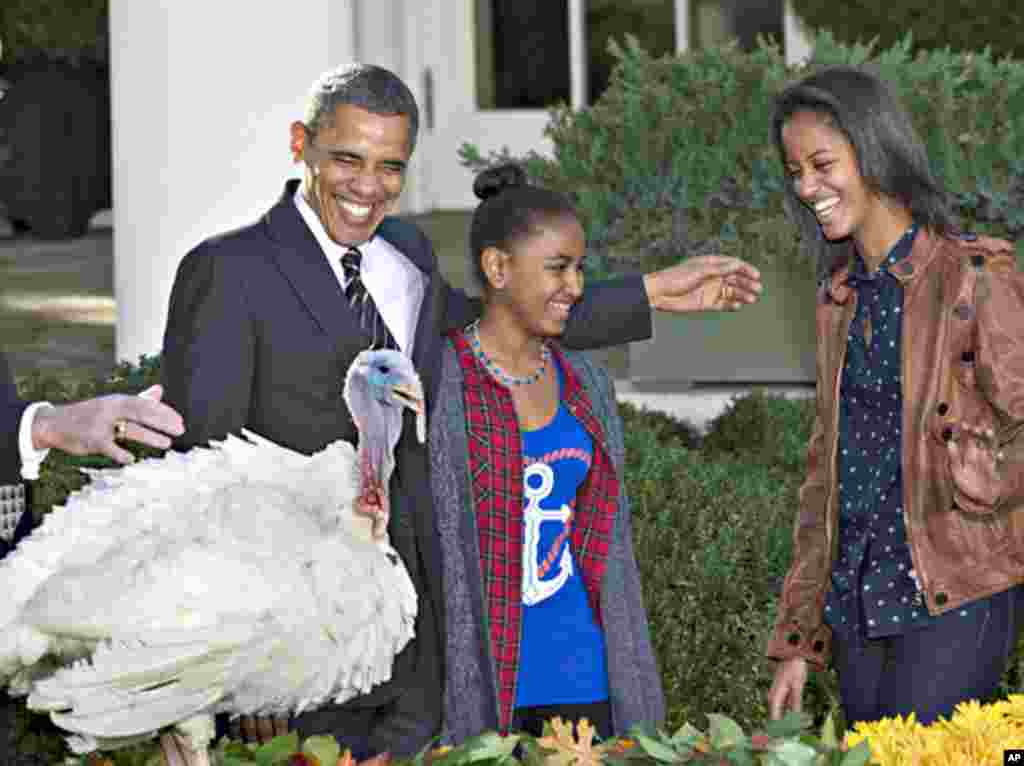 President Barack Obama, with daughters Sasha (l) and Malia carries on the Thanksgiving tradition of saving a turkey from the dinner table with a "presidential pardon," Nov. 21, 2012, in the Rose Garden of the White House.