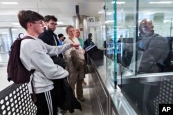 Piet De Staercke, his wife Jill Bornauw, and their eldest son Stan De Staercke watch their youngest Tuur de Staercke, get screened by a Customs Border Protection officer at Washington Dulles International Airport in Virginia, April 1, 2024. (AP Photo/Manuel Balce Ceneta)