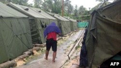 FILE - A man walking between tents at Australia's regional processing centre on Manus Island, in Papua New Guinea.