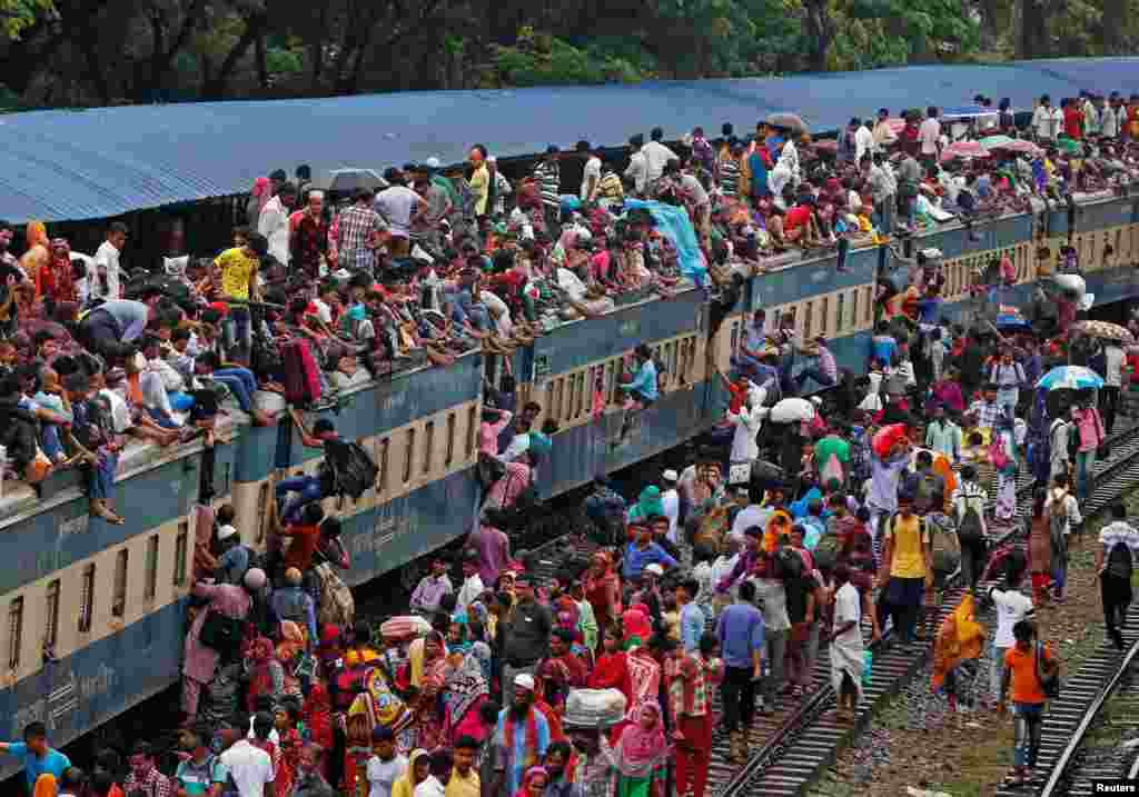People climb to board an overcrowded passenger train as they travel home to celebrate Eid al-Fitr festival, which marks the end of the Muslim holy fasting month of Ramadan, at a railway station in Dhaka, Bangladesh.