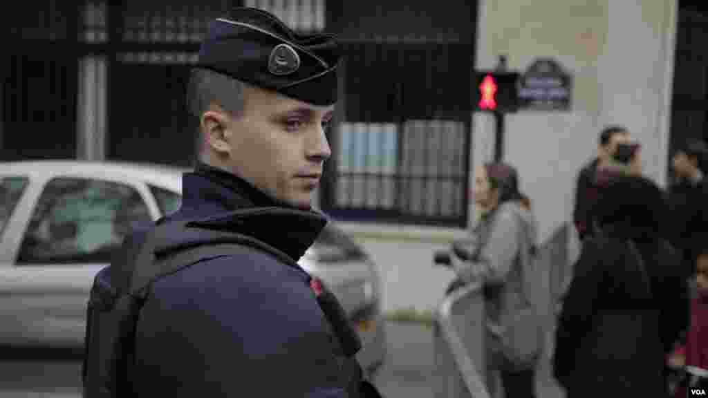 A police officer stands guard at a memorial outside the Bataclan Concert Hall a day after more than 120 people were killed in a series of attacks in Paris, Nov. 14, 2015.