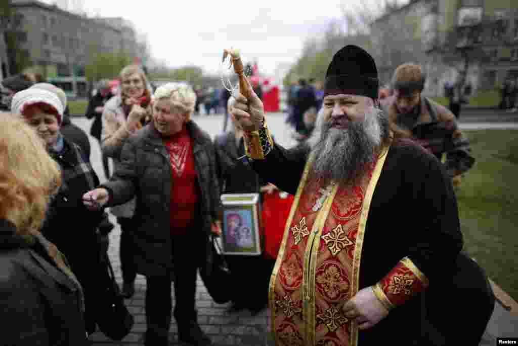 A Ukrainian Orthodox priest sprinkles holy water on worshippers outside a regional government building during Easter in Donetsk, eastern Ukraine, April 20, 2014. 