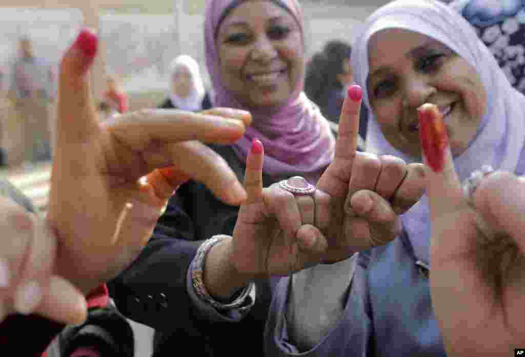 Perempuan-perempuan Mesir menunjukkan jari bertinta tanda telah memberikan suara di tempat pemungutan suara di Kairo (14/1). (AP/Amr Nabil)