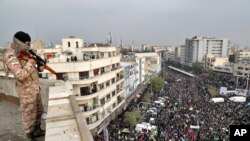 Seorang tentara Iran berjaga dari atas gedung bertingkat, saat berlangsungnya demonstrasi pro-pemerintah di Teheran, Iran, memprotes keras kenaikan harga bahan bakar yang diberlakukan pemerintah, 25 November 2019.
