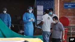 In this June 10, 2020 photo, people enquire about their relatives from a health worker at a COVID designated hospital in New Delhi, India, where cases have shot up with restrictions easing in recent weeks.
