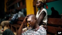 A man wounded in fighting between anti-Balaka and ex-Seleka troops sits on the floor in the Community Hospital in Bangui, Central African Republic, Dec. 20, 2013.
