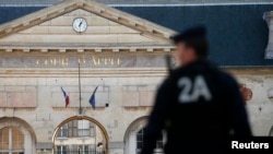 FILE - A police officer secures the entrance of the Appeals Court of Versailles for the arrival of vehicles transporting Mehdi Nemmouche, the French national suspected of the shooting attack in the Brussels Jewish Museum in May that left four people dead.
