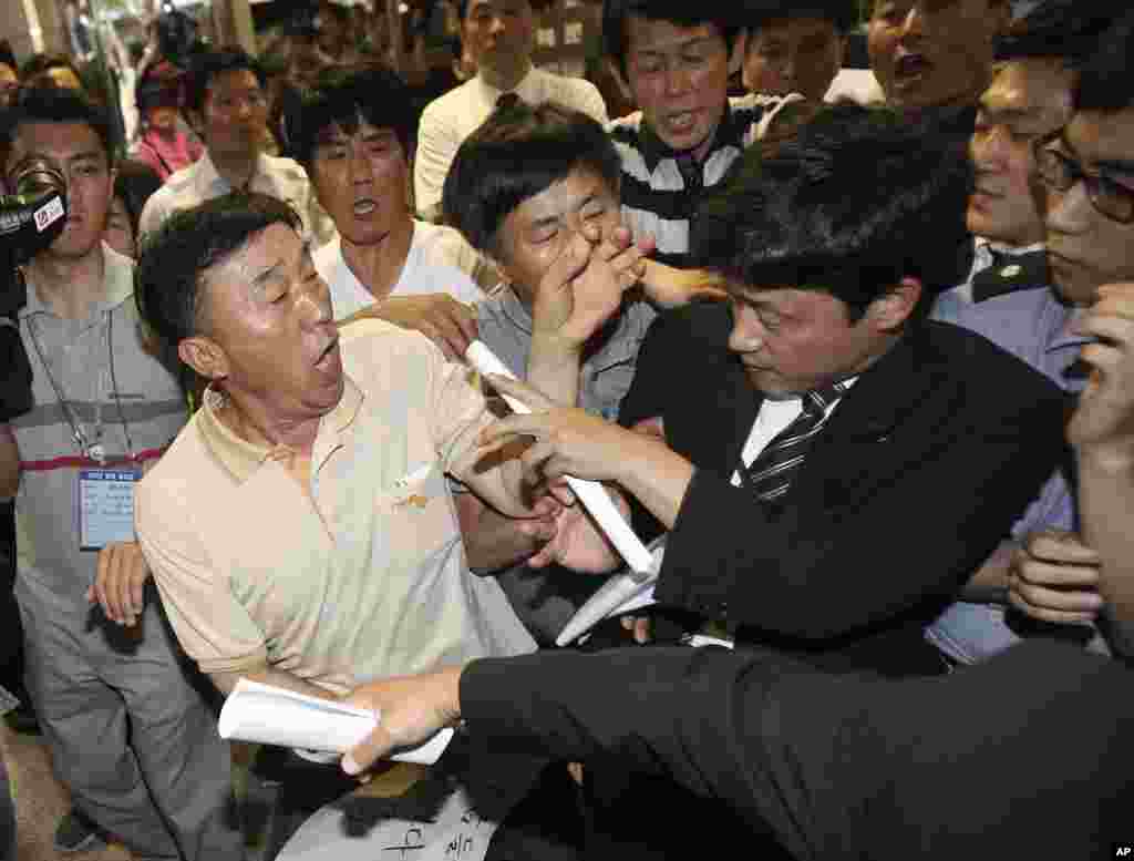 Family members of passengers aboard the sunken ferry Sewol struggle with a security officer, right, while attempting to attend a pretrial hearing for the ferry's crew members at Gwangju District Court in Gwangju, South Korea, June 10, 2014.