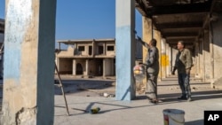 Orang-orang mengecat ulang sebagian rumah mereka yang rusak selama perang rezim Assad, di Saraqib, di pinggiran Idlib, Suriah, 15 Januari 2025. (Foto: Mosa'ab Elshamy/AP Photo)