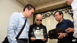 Liu Xia, wife of jailed Nobel Peace Prize winner and Chinese dissident Liu Xiaobo, holds a portrait of him during his funeral in Shenyang in northeastern China's Liaoning Province, July 15, 2017.