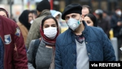 Sepasang pasutri Iran mengenakan masker agar tak tertular virus korona, berjalan di Grand Bazaar, Teheran, Iran, 20 Februari 2020. 