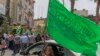 Seorang gadis Palestina melihat keluar dari kendaraan keluarganya dan mengibarkan bendera hijau Hamas di kota Ramallah, Tepi Barat, Jumat, 21 Mei 2021. (Foto: AP)