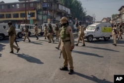 Indian police men watch as Kashmiri men carry the body of Mohammad Saleem Malik during his funeral procession in Srinagar, Indian controlled Kashmir, Sep. 27, 2018. Residents say government forces shot and killed the young man early Thursday during a raid.