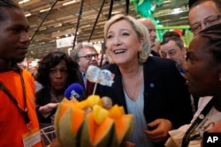 French far-right leader Marine le Pen smiles at the French Caraibean islands stand as she visits the Agriculture Fair Tuesday, Feb. 28, 2017 in Paris.