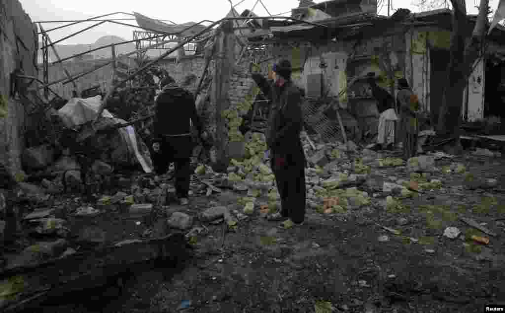 A man takes a photograph with his mobile phone of a house that was damaged by a bomb blast in Quetta, Pakistan, January 11, 2013.