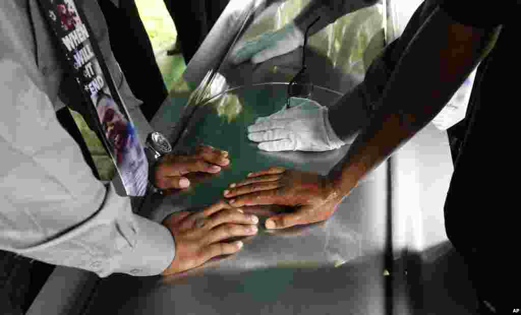 Pallbearers touch the casket of Alton Sterling after placing it at the interment site at the Mount Pilgrim Benevolent Society Cemetery in Baton Rouge, Louisiana. Sterling was shot July 5 outside a convenience store in an encounter with police that was caught on video.