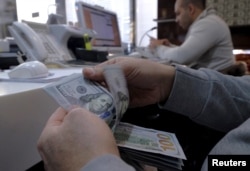 A money changer counts out U.S. dollars for a customer in Tehran's business district, Iran, Jan. 20, 2016.