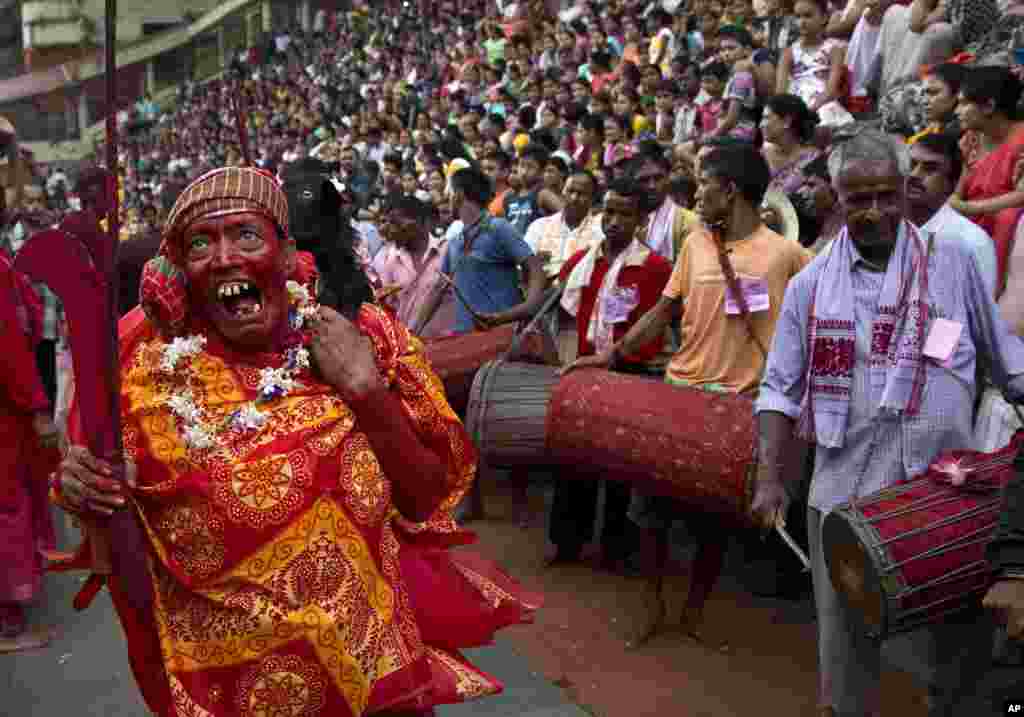 A Hindu priest, face smeared with color and sacrificial blood, carries a goat over his shoulder for sacrifice during the Deodhani festival at the Kamakhya Hindu temple in Gauhati, India.
