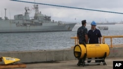 Anggota angkatan laut AS berdiri dekat alat pencari sinyal kotak hitam yang akan digunakan untuk mencari pesawat Malaysia Airlines penerbangan MH370 di Perth, Australia (30/3). (AP/Rob Griffith)