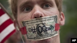 A protester affiliated with the "Occupy Wall Street" protests stands with a US dollar bill taped over his mouth in Zuccotti Park in New York, October 10, 2011.