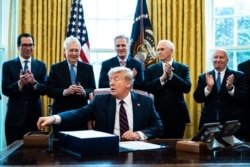 Treasury Secretary Steven Mnuchin, Senate Majority Leader Mitch McConnell, House Minority Leader Kevin McCarthy Vice President Mike Pence and Rep. Kevin Brady applaud President Donald Trump during then bill signing ceremony, March 27, 2020.