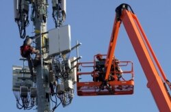 FILE - A Verizon contract crew installs 5G telecommunications equipment on a tower in Orem, Utah, Dec. 3, 2019.