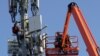 FILE - A Verizon contract crew installs 5G telecommunications equipment on a tower in Orem, Utah, Dec. 3, 2019.
