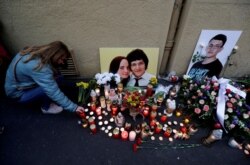 FILE - A woman kneels by a memorial on the first anniversary of the killings of the investigative reporter Jan Kuciak and his fiancee, Martina Kusnirova, in Bratislava, Slovakia, Feb. 21, 2019.