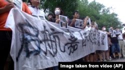 Residents hold up a banner which reads: "Refugees from Qihang Apartment Complex appeal" outside a hotel where officials held daily media conferences in northeastern China's Tianjin municipality, Aug. 16, 2015.