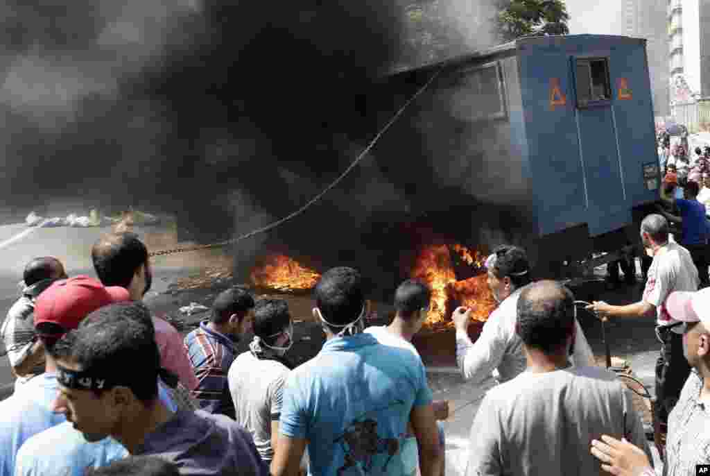 Supporters of ousted Islamist President Mohammed Morsi surround a burning police car during clashes with Egyptian security forces in Cairo's Mohandessin neighborhood, Egypt, August 14, 2013. 