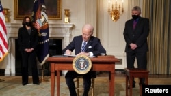 Presiden AS Joe Biden menandatangani perintah eksekutif didampingi Wakil Presiden Kamala Harris dan penasihat sains Gedung Putih Eric Lander di Gedung Putih di Washington, AS, 27 Januari 2021. (Foto: REUTERS/Kevin Lamarque)