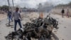 Security forces and civilians gather near the wreckage after a suicide car bomb attack that targeted the city's police commissioner in Mogadishu, Somalia, July 10, 2021.