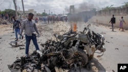 Security forces and civilians gather near the wreckage after a suicide car bomb attack that targeted the city's police commissioner in Mogadishu, Somalia, July 10, 2021.
