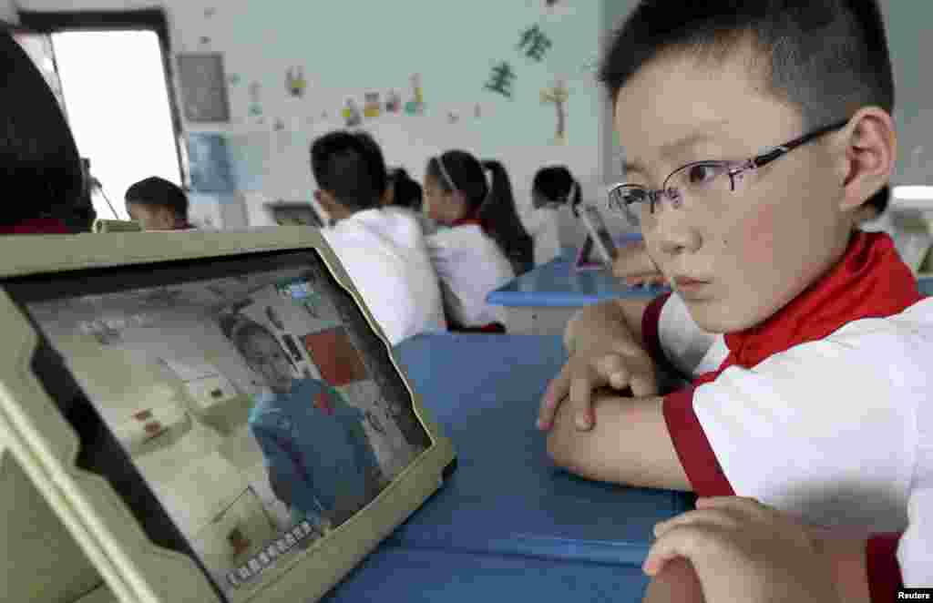 A student looks at his iPad at a primary school in Quzhou, Zhejiang province, China, as his class watches a live broadcast of a lecture given by Shenzhou-10 spacecraft astronauts on the Tiangong-1 space module.