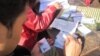 An election worker gives out identification cards in Durbar Square, Kathmandu, Nov. 17, 2013. (Aru Pande/VOA) 