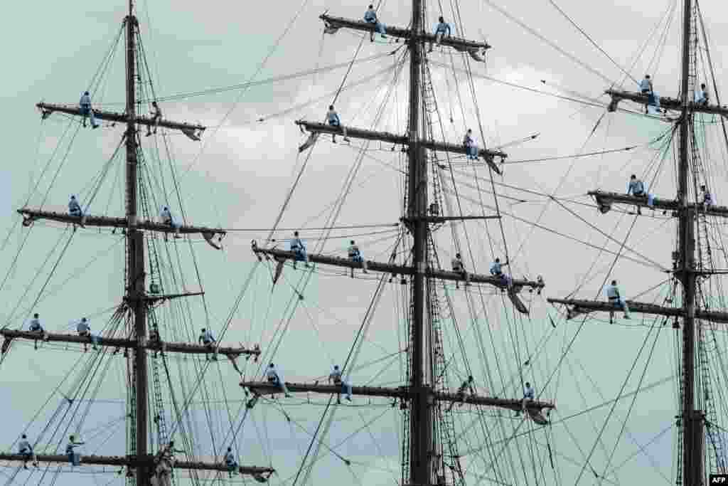 Brazilian Navy Academy students sit on a boat's mast during a ceremony marking the arrival of the Olympic flame at their Academy in Rio de Janeiro ahead of the Rio 2016 Olympic Games.