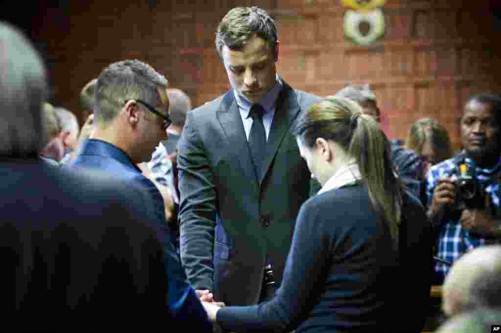 Oscar Pistorius cries as he prays with his sister Aimee and brother Carl at his indictment at the magistrates court in Pretoria, August 19, 2013.
