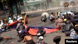 Des manifestants s'accroupissent après que la police a ouvert le feu pour disperser une manifestation anti-coup d'État à Mandalay, au Myanmar, le 3 mars 2021.